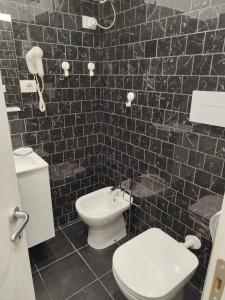 bagno con servizi igienici e parete piastrellata nera. di Royal Naples a Napoli Altre 3 foto