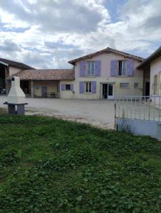 una grande casa con finestre viola e un prato di La Maison de l'Ormeau a Montauban