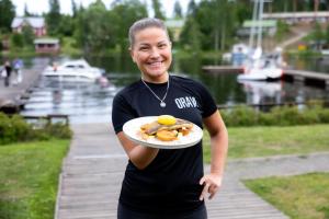 a woman is holding a plate with food on it at Oravi Apartments in Oravi