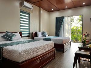 a bedroom with two beds and a window and a desk at The Green House Homestay in Ninh Binh