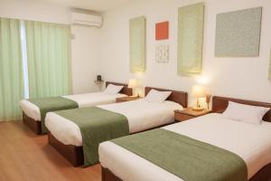 ein Hotelzimmer mit 3 Betten und grüner Bettwäsche in der Unterkunft K Cottage in Fujikawaguchiko