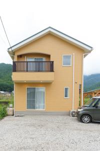 ein gelbes Haus mit einem davor geparkt in der Unterkunft K Cottage in Fujikawaguchiko