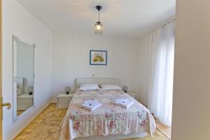 a white bedroom with a bed and a mirror at Pension Alba in Podstrana