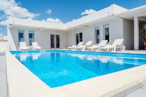 a swimming pool with chairs and a house at Villa Green in Mostar