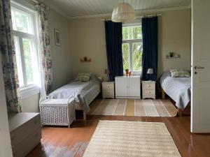 a bedroom with two beds and two windows at Pihlajaharju Countryside Escape in Somero