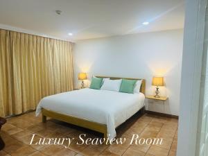 a bedroom with a white bed and two lamps at Surin Bay Inn in Surin Beach