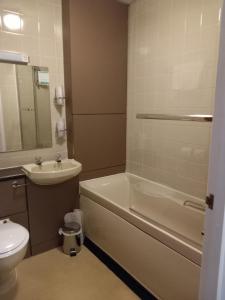 a bathroom with a tub and a sink and a toilet at Sandown Park Lodge in Esher +15 photos