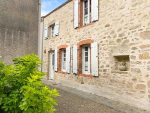 un edificio de ladrillo con ventanas blancas y una maceta en Le logis de la Forge à 10 min du Puy duFou, en Mortagne-sur-Sèvre