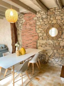 Una mesa y sillas en una habitación con una pared de ladrillos. en Le logis de la Forge à 10 min du Puy duFou, en Mortagne-sur-Sèvre 12 fotos más