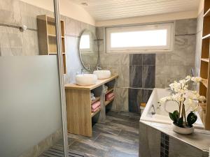 Un baño con lavabo, bañera y espejo. en Le logis de la Forge à 10 min du Puy duFou, en Mortagne-sur-Sèvre