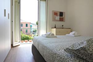 a white bedroom with a bed and a large window at Alma House in Finale Ligure