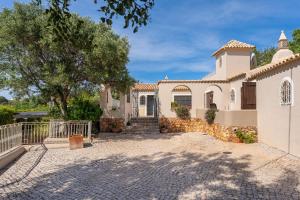 a large white house with a stone driveway at The Quinta - 3 Bedroom ensuite Villa, Swimming Pool, Beautiful Gardens, water features and lake in Almancil
