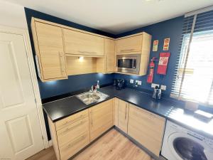 a small kitchen with wooden cabinets and a sink at Casa Crusoe - Part of the The Bay Filey Holiday Village with pool, gym and direct beach access, pub, restaurant, tennis and meadows walks in Reighton