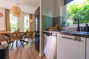 Cozy No 2 Wellness Villa Hottub, Sauna en houtkachel في Hernen: مطبخ مع حوض وطاولة وكراسي