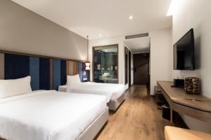 a hotel room with two beds and a television at Sapphire Mandala Mui Ne First Class in Mui Ne