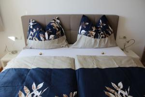 Bett mit blauer und weißer Bettwäsche und Kissen in der Unterkunft Stern Apartments Fontanella in Fontanella