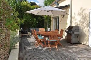 einen Tisch und Stühle mit einem Sonnenschirm und einem Grill in der Unterkunft Maison à la campagne proche Disney in Couilly-Pont-aux-Dames