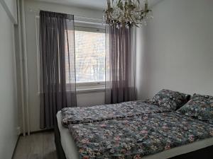 a bedroom with a bed and a window with a chandelier at City Apartment Hilla in Rovaniemi