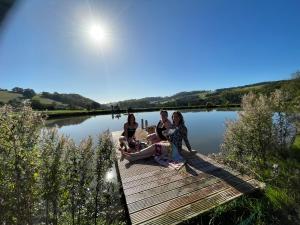 a group of people sitting on a dock on a lake at Rural self contained cosy pod house. in Garway
