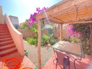 a patio with a table and chairs under a pergola at Tigmi home in Mirleft +3 photos