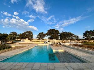 a swimming pool with a bench and a blue sky at Trullo Dimora Podere Papilio in Noci