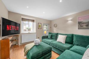 ein Wohnzimmer mit einem grünen Sofa und einem Fernseher in der Unterkunft Fable Cottage Luxurious Stay in Bakewell