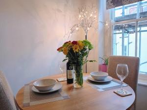 a table with two plates and a vase of flowers at Alnwick Town Centre Apartment in Alnwick