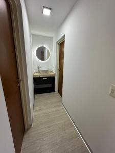 einen Flur eines Badezimmers mit einem Waschbecken und einem Spiegel in der Unterkunft Amaneceres patagónico in Puerto Madryn