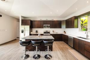 een keuken met houten kasten en een eiland met barkrukken bij Contemporary Villa 3 BD 3BA Pool in Playa Flamingo