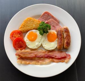 a plate of breakfast food with eggs bacon and toast at Surin Bay Inn in Surin Beach