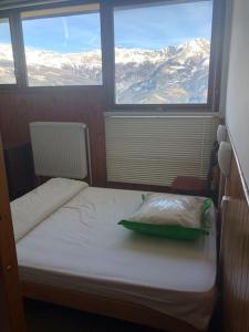 a small room with a bed and two windows at Duplex Praloup in Uvernet-Fours