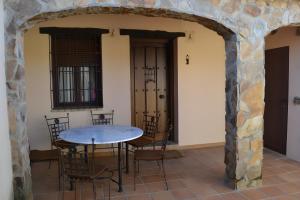 a table and chairs in a room with a stone wall at Casa Rural El Gamo in Fuente Obejuna