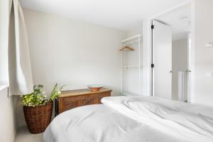a white bedroom with a bed and a potted plant at Appartementen aan het water in Heeg