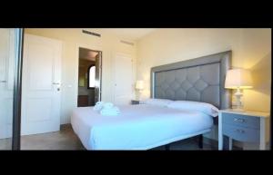 ein Schlafzimmer mit einem großen weißen Bett und einem Spiegel in der Unterkunft APARTAMENTO DUPLEX con piscinas y MARAVILLOSAS VISTAS AL MAR in Estepona