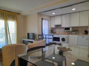 eine Küche mit Glastisch und weißen Schränken in der Unterkunft APARTAMENTO DUPLEX con piscinas y MARAVILLOSAS VISTAS AL MAR in Estepona