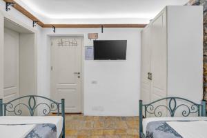 two beds in a room with a tv on the wall at The Well House - UNESCO in Berat