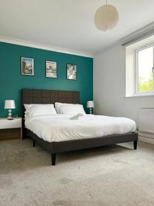 ein Schlafzimmer mit einem großen Bett mit einer grünen Wand in der Unterkunft Beautiful 2-Bed City Centre Apartment with Balcony in Milton Keynes
