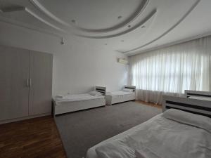 a white room with two beds and a large window at GUESTO HOSTEL in Tashkent +60 photos