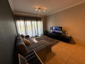 Una sala de estar con un sofá y un televisor de pantalla plana. en Casa de Férias Lucena, en Lourinhã