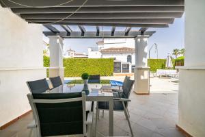 a patio with a table and chairs under a pergola at Villa Caballa in Roldán