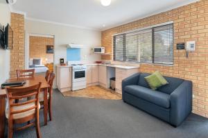 a living room with a blue couch and a kitchen at Begonia City Motor Inn in Ballarat