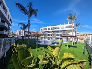 a resort with a pool and palm trees and umbrellas at Poolside 2BR apartment Villamartin in Alicante