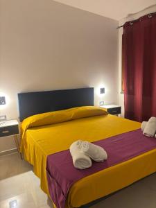 a bedroom with a yellow bed with towels on it at Oriente Camere in San Nicola Arcella