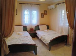 two beds in a room with windows and curtains at Veronika house Under Meteora in Sarakína
