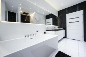Un baño blanco con lavabo y espejo. en White Luxury Apartment, en Katowice