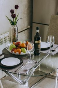 a table with a plate of fruit and a bottle of wine at Dina Lux Iasi Apartment in Iaşi