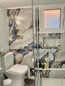 a bathroom with a toilet and a glass shower at Kalimera Apartment in Kalymnos +22 photos