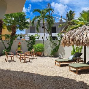 a patio with chairs and tables and palm trees at BnBBonaire near the ocean in Kralendijk