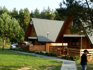Ein Mann steht vor einer Blockhütte. in der Unterkunft Cicha Przystań in Sasino