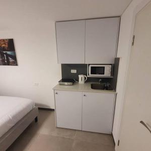 a bedroom with a bed and a white cabinet with a microwave at Ryo 17 דירה במלון בוטיק 2 דקות מטיילת בת ים in Bat Yam